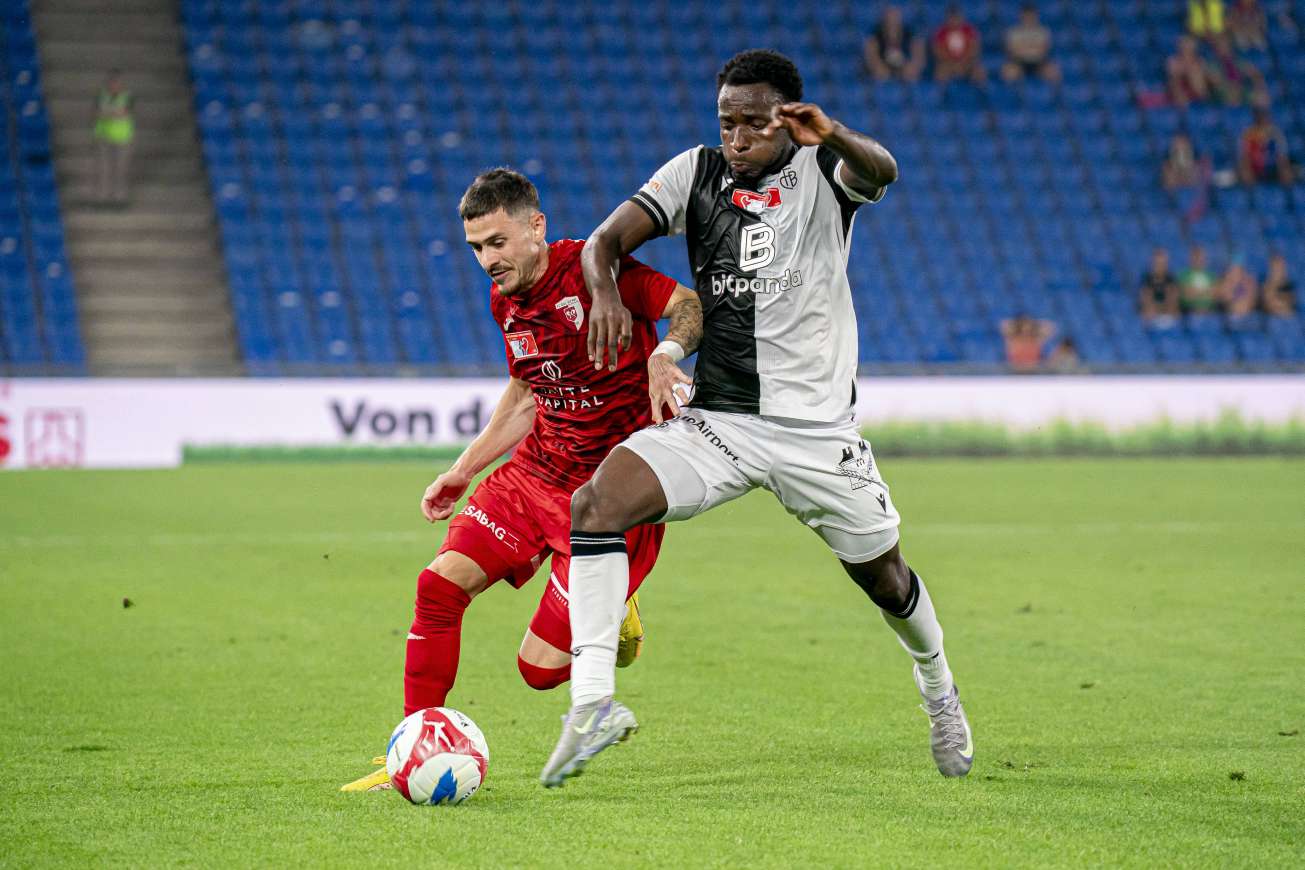 Philip Otele (R) challenges an opponent for the ball