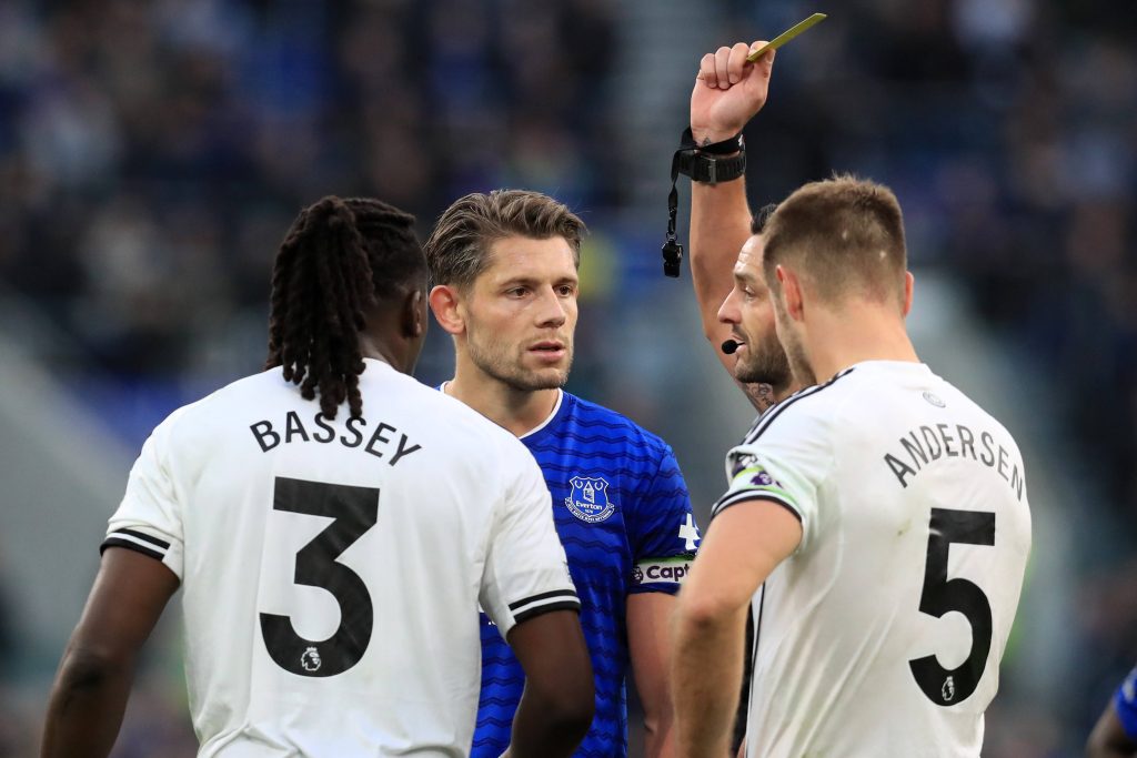 Referee Andy Madley shows a yellow card to Calvin Bassey of Fulham and James Tarkowski of Everton
