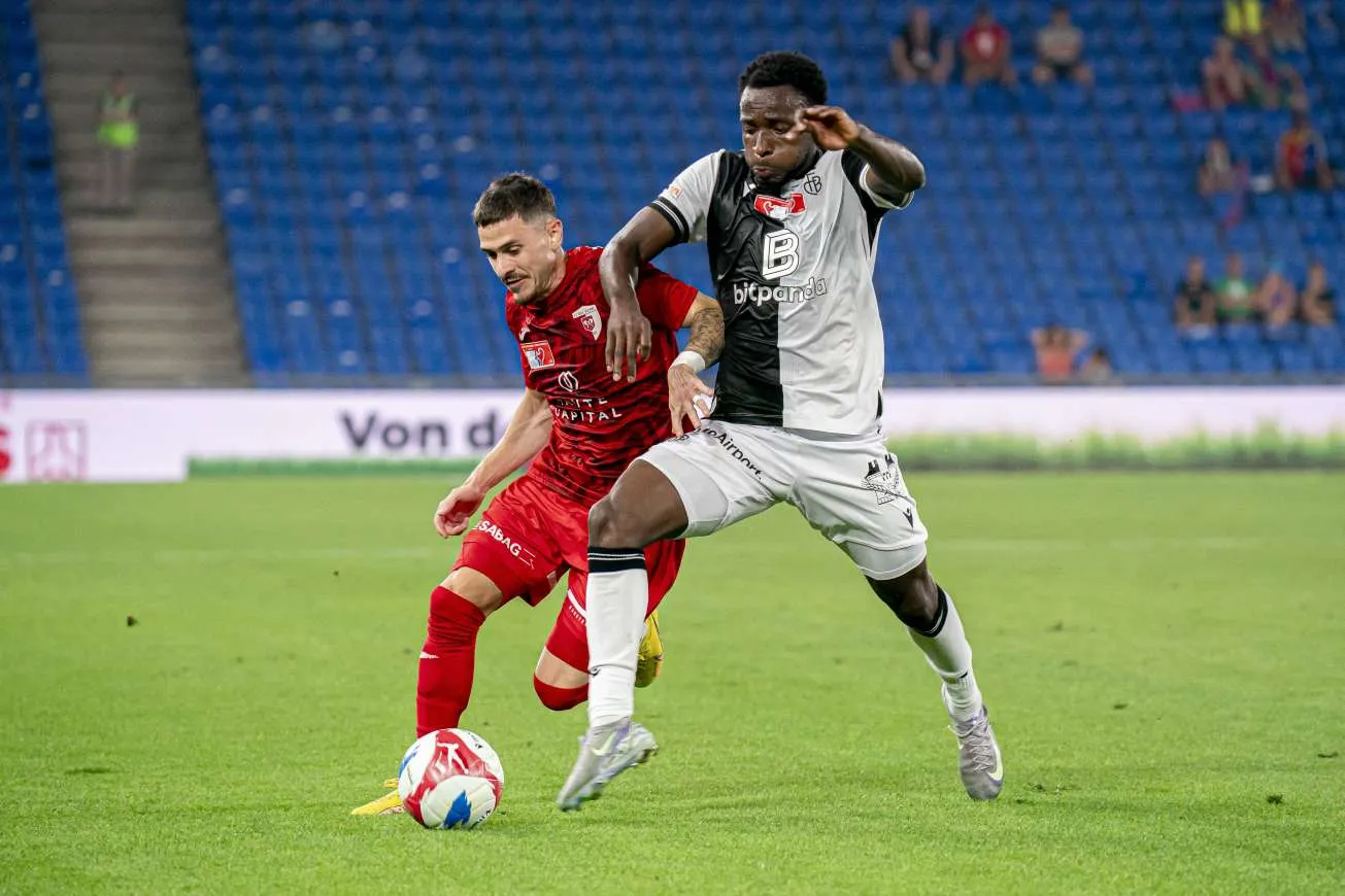 Philip Otele (R) challenges an opponent for the ball