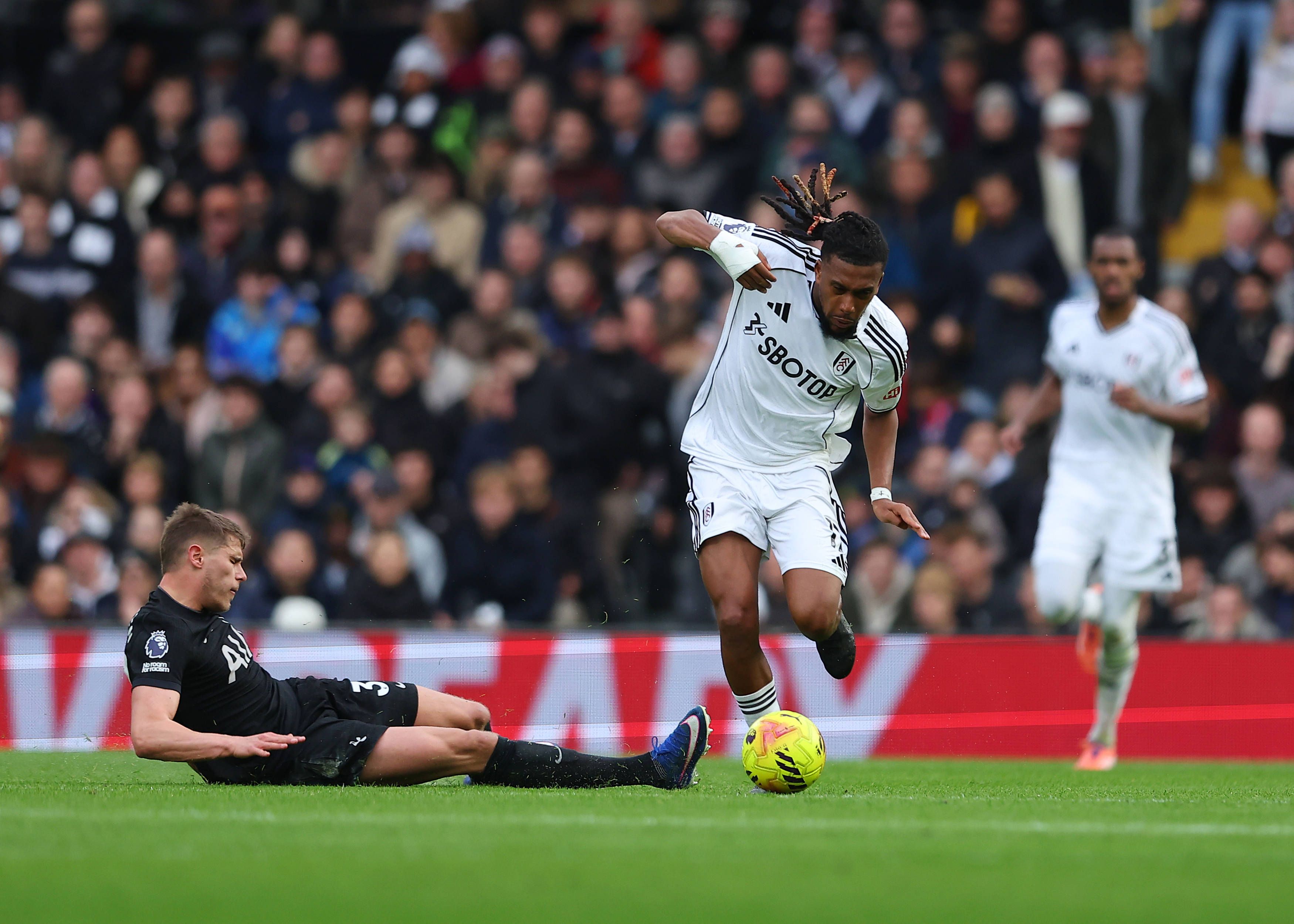 Alex Iwobi of Fulham challenged by Micky van de Ven of Tottenham Hotspur
