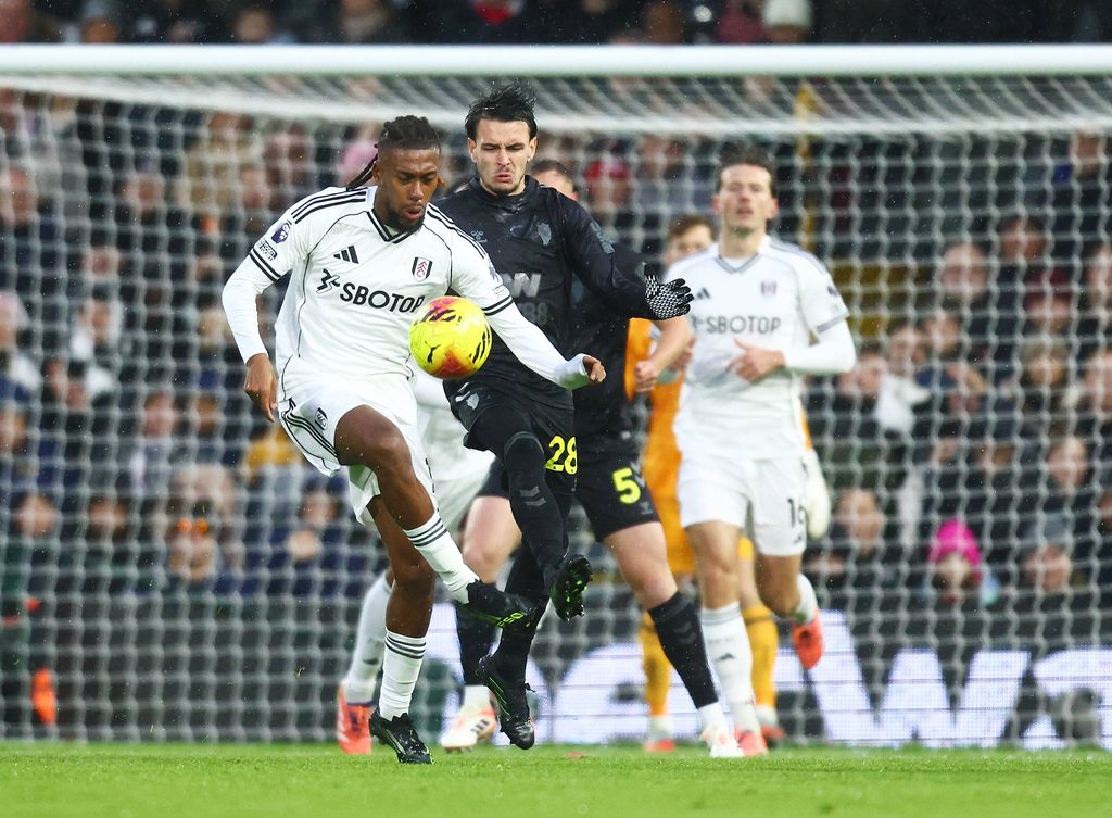 Alex Iwobi slides the ball past Wilson Isidor in the Premier League game between Fulham and Sunderland