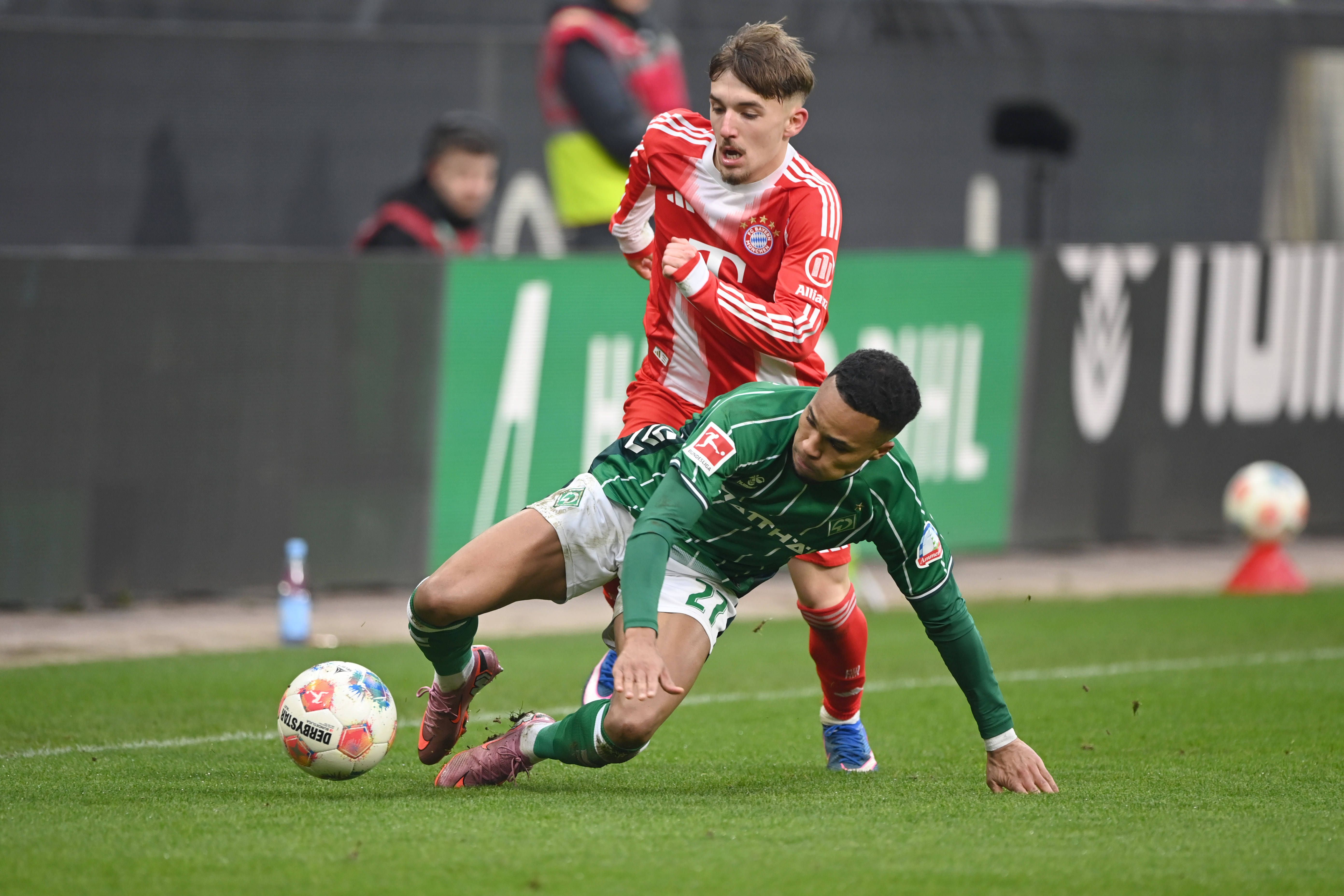 Felix Agu battles for the ball with Lennart Karl in Werder Bremen's loss to Bayern Munich