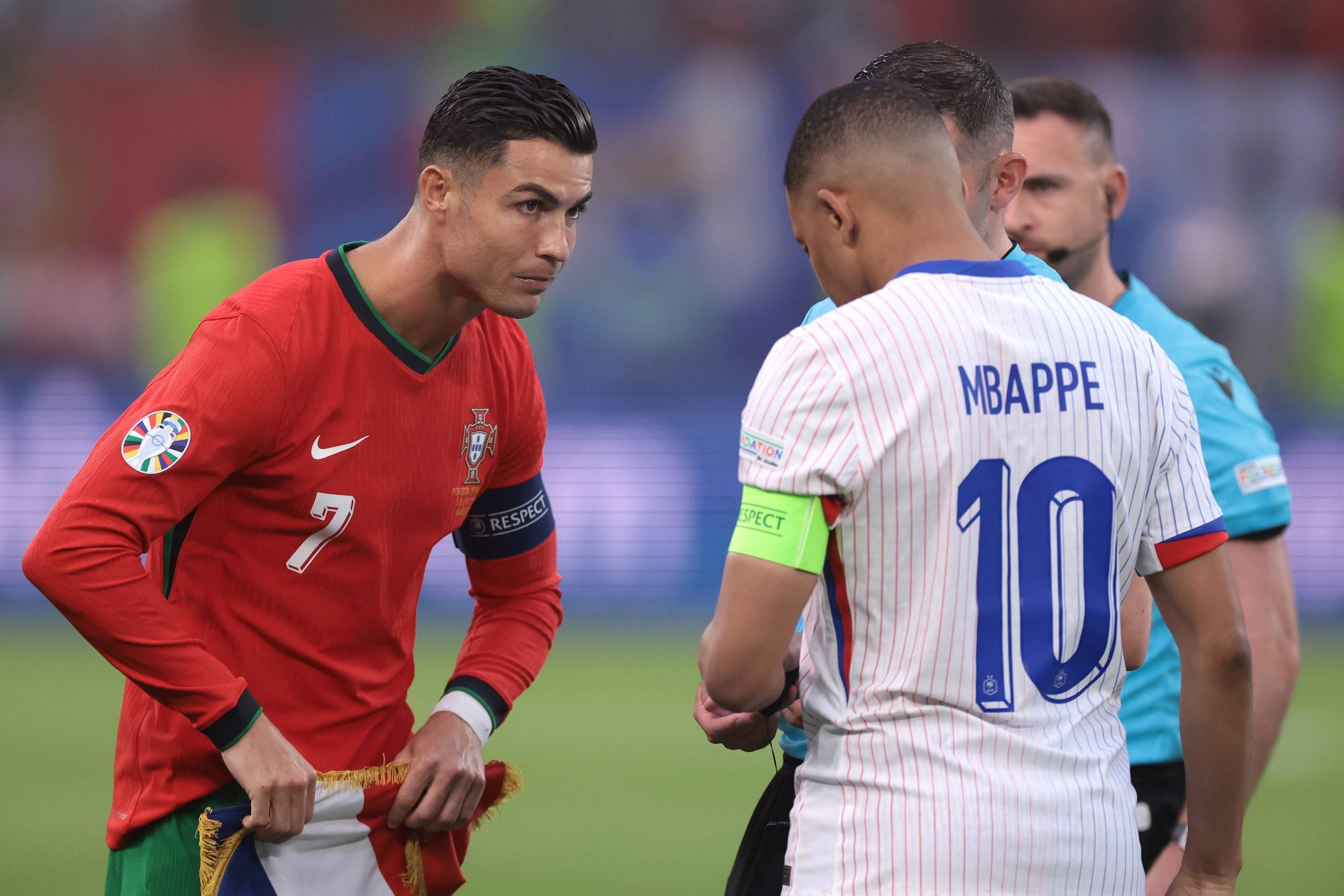 The Referee Michael Oliver of England looks on as Cristiano Ronaldo of Portugal exchanges pennants with Kylian Mbappe of France