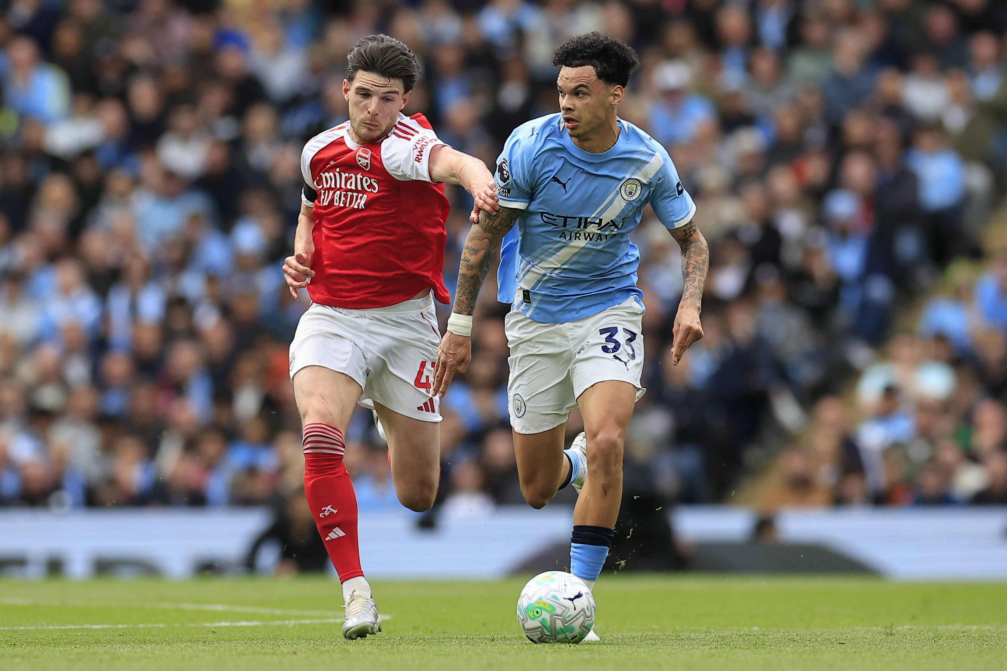 Nico O Reilly is challenged by Declan Rice during the Premier League match between Manchester City and Arsenal at the Etihad Stadium