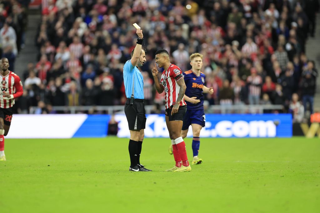 Referee Peter Bankes left issues a yellow card to Reinildo Mandava during the Premier League match at the Stadium of Light, Sunderland